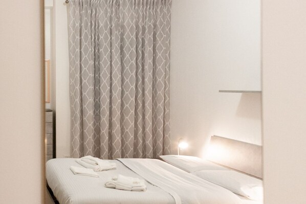 Una habitación de hotel con una cama, cabecera y cortina.