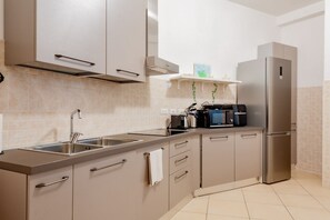 Una cocina moderna con electrodomésticos de acero inoxidable, armarios color beige y salpicadero de azulejos.