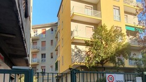 Un immeuble résidentiel fermé, doté de nombreux balcons, avec un ciel dégagé et un panneau indiquant la limite de vitesse.