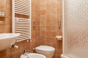 Baño con lavabo, bidé, inodoro y cabina de ducha.