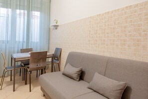 Un espace de vie comprenant un canapé, des fauteuils, une table et un mur recouvert de carreaux.