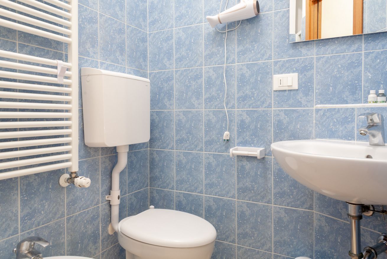 Ein Badezimmer mit Toilette, Waschbecken und einem an der Wand montierten Fön.