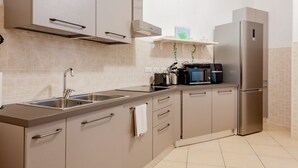 Une cuisine moderne dotée d’appareils électroménagers en acier inoxydable, de meubles de couleur beige et d’un dosseret carrelé.