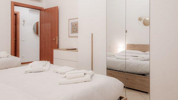 Une chambre d’hôtel avec un lit, une armoire en bois, un miroir et une petite table.