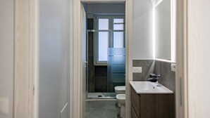 Un baño pequeño con ducha, inodoro y lavamanos.