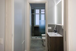 Une petite salle de bain comprenant une douche, des toilettes et un lavabo.