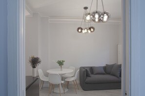 A modern living room with a grey sofa, white chairs, a round table, and a hanging spherical light fixture.