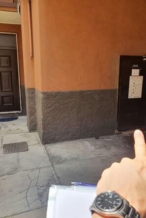 A hand pointing towards a door with a calendar on the wall.