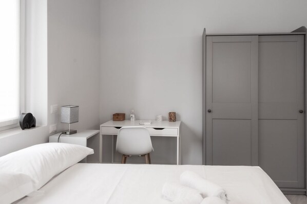 Une chambre à coucher comprenant un lit, un bureau, une chaise, une armoire et une lampe.