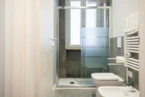 Un baño moderno con ducha de vidrio, inodoro y lavabo.