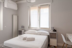 A bedroom with a bed, bedside tables, a desk, and a radiator. - PERGOLESI, 6 - CONSALVI · Accogliente e moderno a due passi da tutto (Milano)