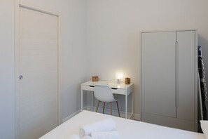 Une chambre à coucher comprenant un lit, un bureau, une chaise et une armoire.