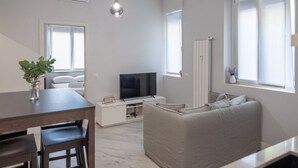 Una sala de estar moderna con sofá, televisor, mesa de comedor y sillas.