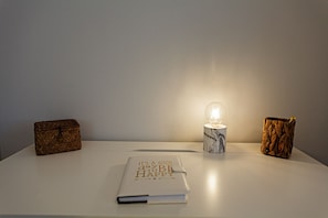 Una mesa con un cuaderno, una lámpara y dos cajas decorativas.