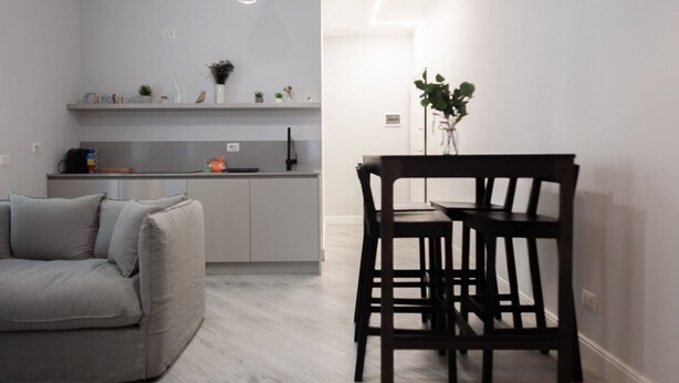 Una cocina moderna con armarios grises, una mesa de comedor con sillas y un sofá.