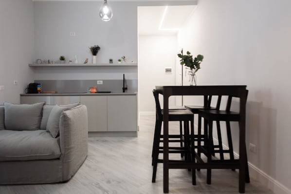 A modern kitchen with grey cabinets, a dining table with chairs, and a sofa.