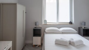 Un dormitorio con cama, dos mesitas de noche, un armario y una ventana con vistas.