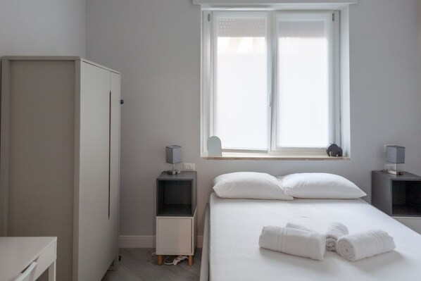 Un dormitorio con cama, dos mesitas de noche, un armario y una ventana con vistas.
