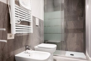 A modern bathroom with a shower enclosure, a sink, and a toilet.
