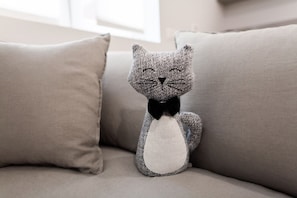 A plush toy cat with a black bow tie sitting on a beige sofa. - PERGOLESI, 6 - VILLANO · Accogliente e moderno nel cuore dello shopping (Milano)