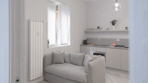Una cocina moderna con armarios blancos, horno empotrado y ventana.