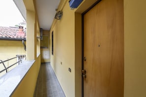 Un pasillo con una puerta de madera, un ventanal pequeño y suelo de baldosas.