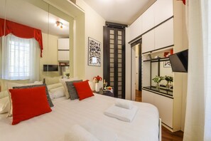 Una habitación de hotel con una cama, un escritorio, un espejo y un armario.