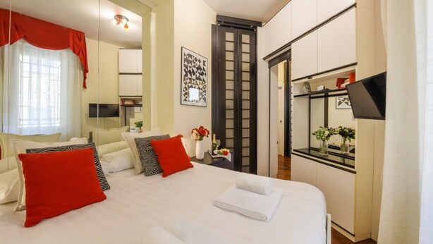 A hotel room with a bed, a desk, a mirror, and a wardrobe.
