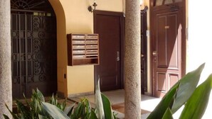 A building entrance with a metal gate, a wooden mailbox, and a door.