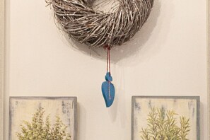 A wall with a woven wreath and a blue hanging ornament.