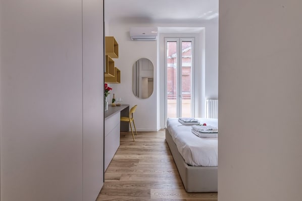 Ein Schlafzimmer mit Bett, Schreibtisch, Stuhl und Fenster.