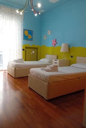 A room with two beds, a window with curtains, a radiator, and a wall with a picture and a lamp. - Stromboli, 22 – Elegante appartamento (Milano)