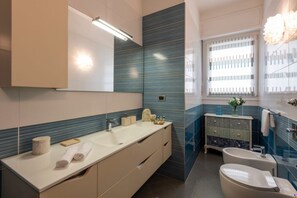 A modern bathroom with a large mirror, a sink, a toilet, and a vanity with drawers.