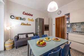 A compact kitchen with a dining area, a refrigerator, an oven, and a clock on the wall. - Stromboli, 22 – Elegante appartamento (Milano)