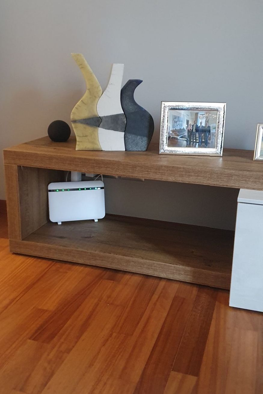Une console en bois sur laquelle reposent un appareil électronique blanc, un objet sphérique noir et deux sculptures abstraites.