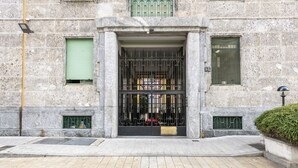 A stone building with a metal gate, a green window, and a small door. - Venini 14 - Tra Centrale e Buenos Aires (Milano)