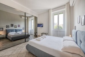A modern hotel room with a large bed, a flat-screen TV, a mirror, and a window with curtains. - Venini 14 - Tra Centrale e Buenos Aires (Milano)