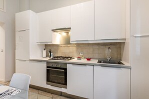Uma cozinha moderna com armários brancos, fogão a gás, forno e pia.