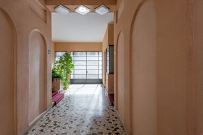 A hallway with a tiled floor, a potted plant, and a door with a window.