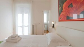 A hotel room with a bed, a radiator, a door, and a painting on the wall. - Verona 12, Porta Romana district (Milano)