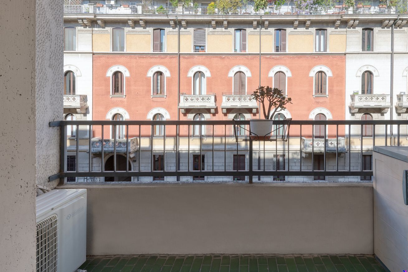 Un balcó amb vista a una filera d'edificis, una planta en test i un radiador.