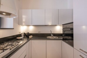 Une cuisine moderne avec des armoires blanches, un évier en acier inoxydable et un four Bosch.