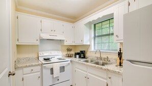 A kitchen with white cabinets, a stove, a sink, and a window with blinds. - Bring the Whole Alumni Crew Close to Ole Miss (Oxford)