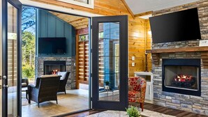 Una sala de estar moderna con chimenea, televisión y comedor con mobiliario de mimbre.