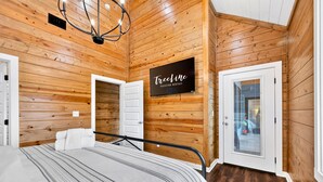 A wooden-paneled room with a bed, a television, and a sign for 'Teline Vacation Rentals'.