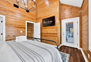 A wooden-paneled room with a bed, a television, and a sign for 'Teline Vacation Rentals'.