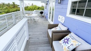A covered porch with wicker furniture, a table, and chairs.