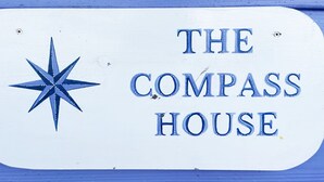 A sign with the text "THE COMPASS HOUSE" and a compass symbol.