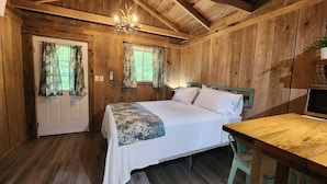 Una camera in una baita di legno con un letto, una scrivania e un lampadario.