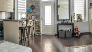 A compact living space with a kitchenette, a dining area with bar stools, a bed, and a small play area with toys.